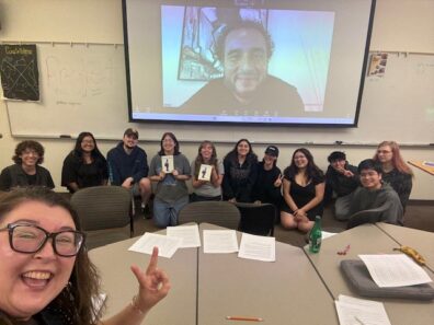 Amy Hernandez Matsumoto takes a  selfie with Javier Zamora via Zoom call and a group of attendees to the event. 