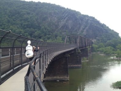 Ruth Boden backpacks with her cello across the historic Potomac River railroad bridge on the Appalachian Trail in Harpers Ferry, WV. Photo credit: Dean Luethi