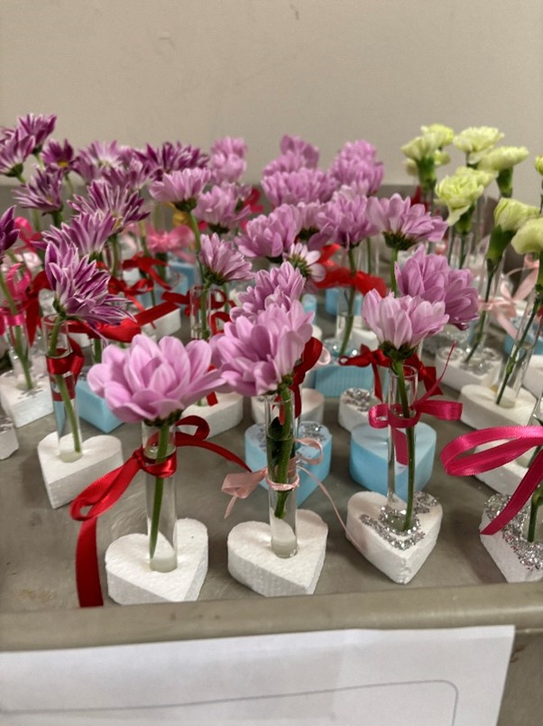 Flowers wrapped in crimson ribbon set in beakers.