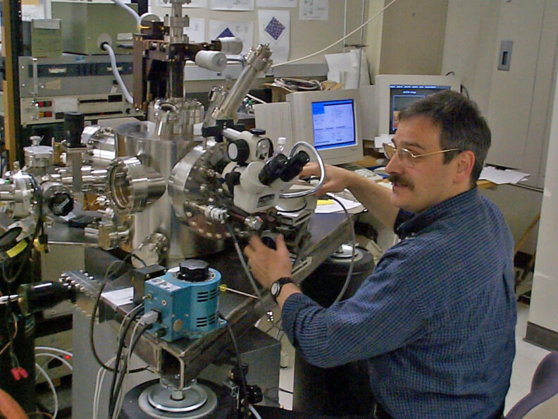 Louis Scudiero sitting at a large microscope in the lab.