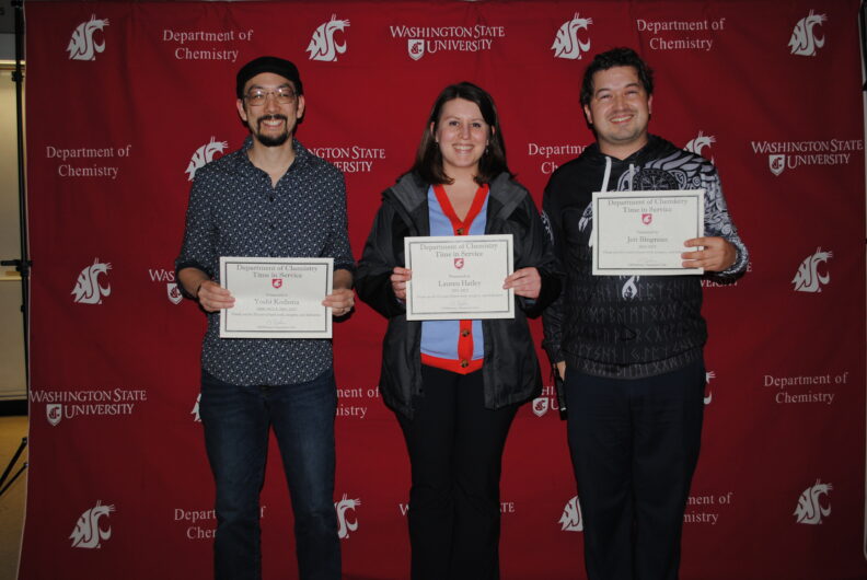 Kodama, Hatley, and Bingman holding their awards in front of a crimson backdrop with the WSU logo.