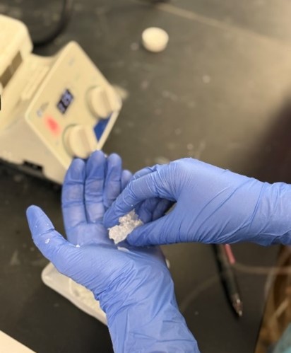 Gloved hands molding material between fingers.