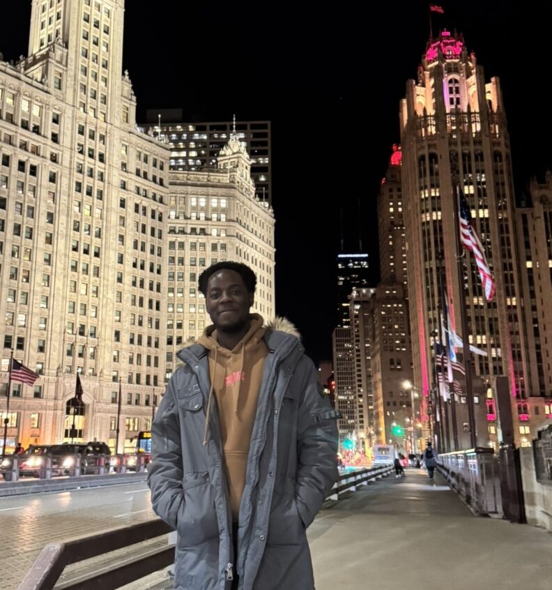 Byron Fisher standing on the side of a street in front of tall buildings.