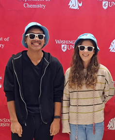 Two chemistry graduates in matching sunglasses and bucket hats.