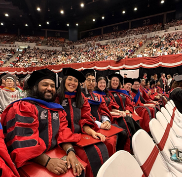 PhD student graduates in regalia at commencement.