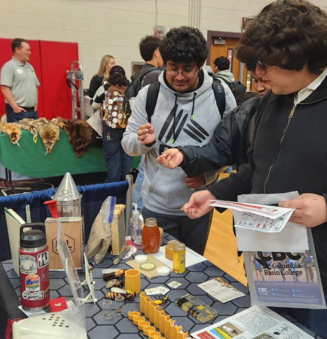 two highschool students interacting with items on the bee program booth at the 2025 Othello Career Showcase