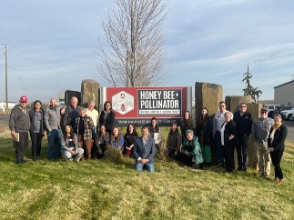 WSU Bee Program Major Donors and WSU Bee Program team standing in front of welcome sign at the Honey Bee Research Facility in Othello, WA