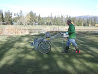 A person applying treatment to grass.