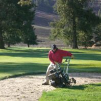 A man working a machine in a sandpit.
