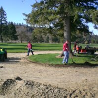 Men working in the dirt and grass.
