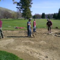 Men with rakes in a sandpit.