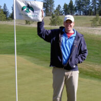 A man holding a golf flag.