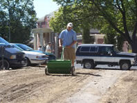 Man pushing a seeder.