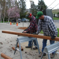 Two people with a beam of wood.