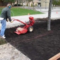 A person pushing a machine in dirt.