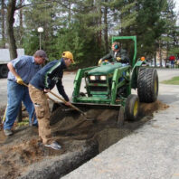 People getting dirt out of a tractor.