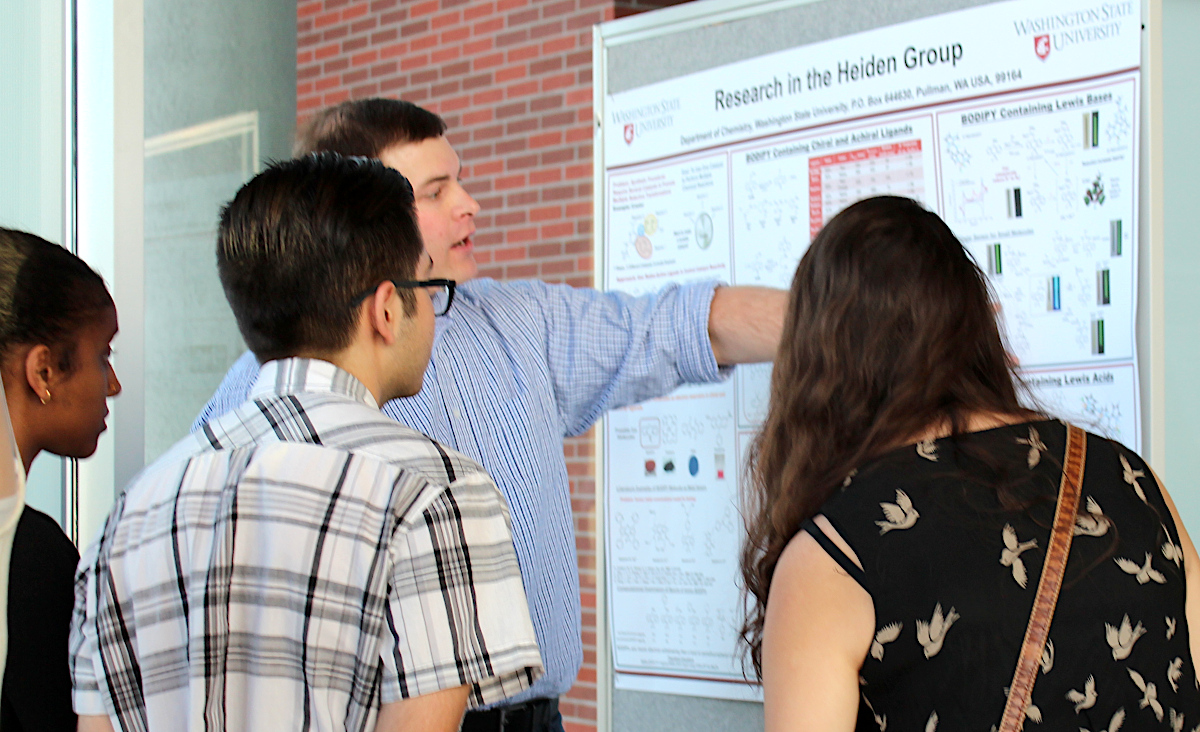 LSAMP students listening to a LSAMP faculty research mentor share his work using a poster as a visual aid.