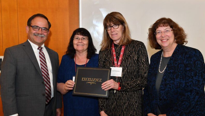 Provost Dan Bernardo and Vice Provost Erica Austin presenting a certificate to Apparel, Merchandising, Design & Textiles.