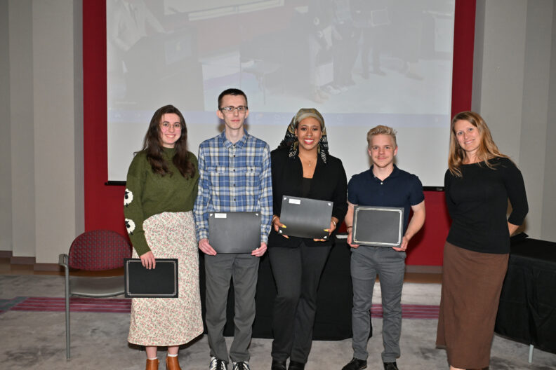 Awardees Emma Louise Miller, Jacob Garrett, Jada Rome, and Aidan Skylstad hold their awards up for the camera as Brooklyn Walter stands at their left.