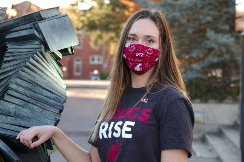 A WSU student wearing a first generation student lapel pin and a Cougs Rise T-shirt.