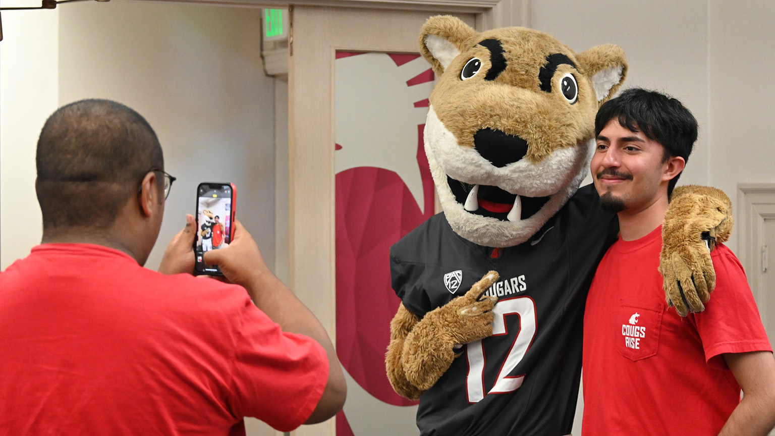 Cougs rise students take smiling pictures with WSU mascot Butch T. Cougar in The Commons Student Center.