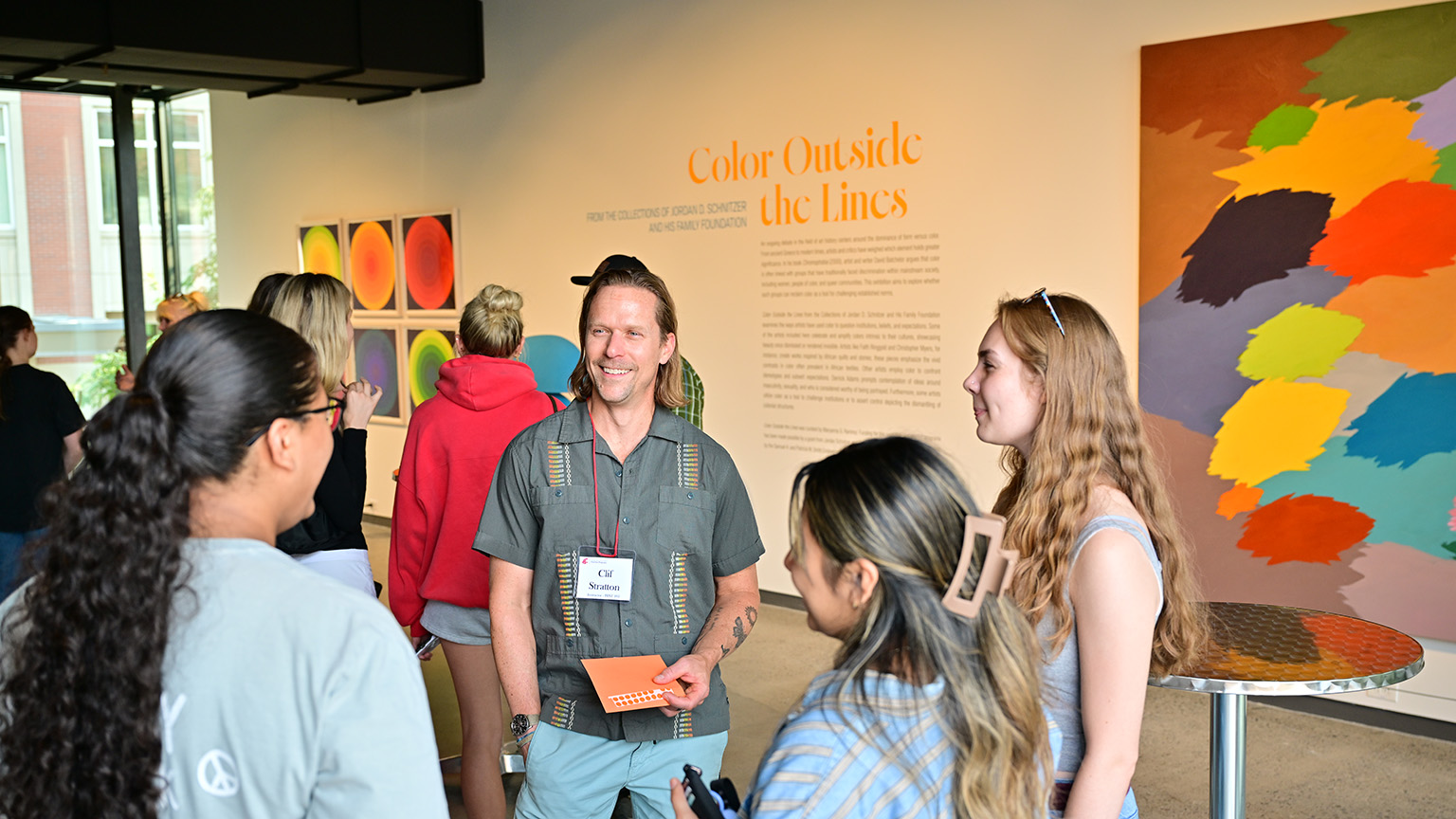 Students speak with faculty member and professor Clif Stratton in the lobby of the Jordan Schnitzer Museum of Art. They are attending the First-Year Program's Night at the Museum event.