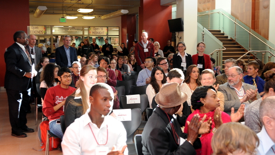 Audience attending the 2014 Distinguished Scholars Celebration event in the CUB. Most audience members are seated in the CUB, but committee members are standing for recognition.