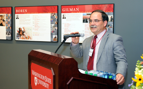 Provost Dan Bernardo gives remarks at the podium placed in front of the primary wall of the Distinguished Scholars Gallery.