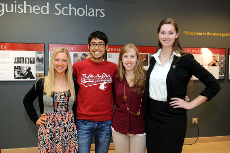 The group of scholars who received Fulbright awards stand together in front of the gallery wall.