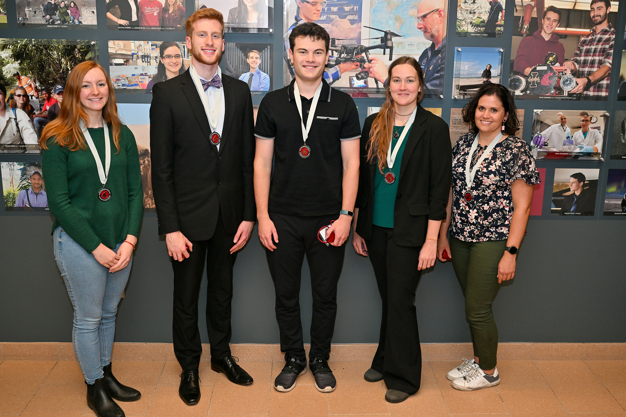 WSU students who are recent distinguished scholarships recipients smile together in front of the WSU Distinguished Gallery wall.