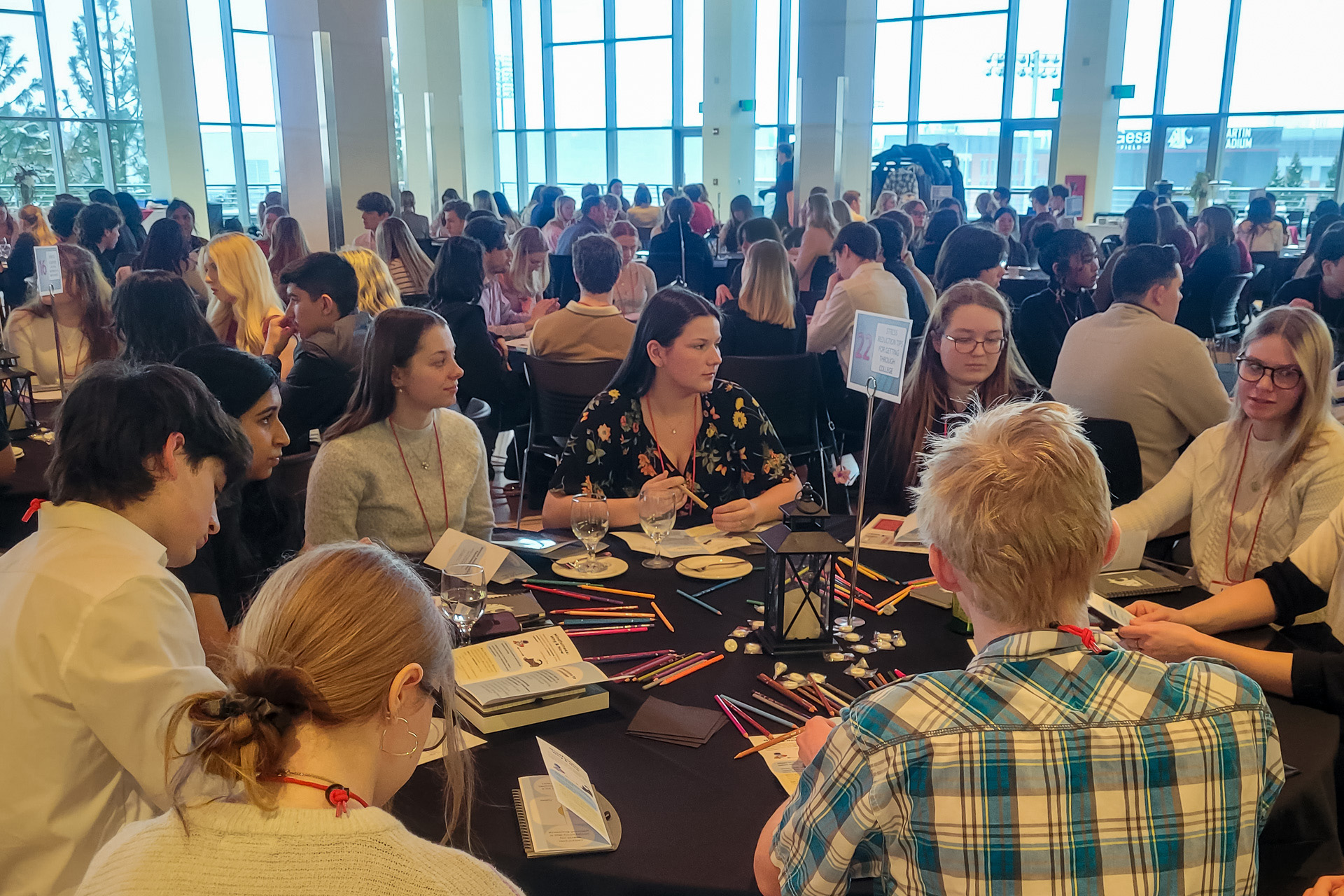 Students seated around a circular table in the CUB Senior Ballroom and engaged in a table discussion at the 2025 WSU Scholars Progression.