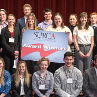 Group photo of SURCA 2019 award winners posing on stage in the CUB auditorium.