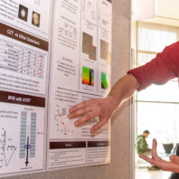 A student points out results on their poster during a SURCA presentation.