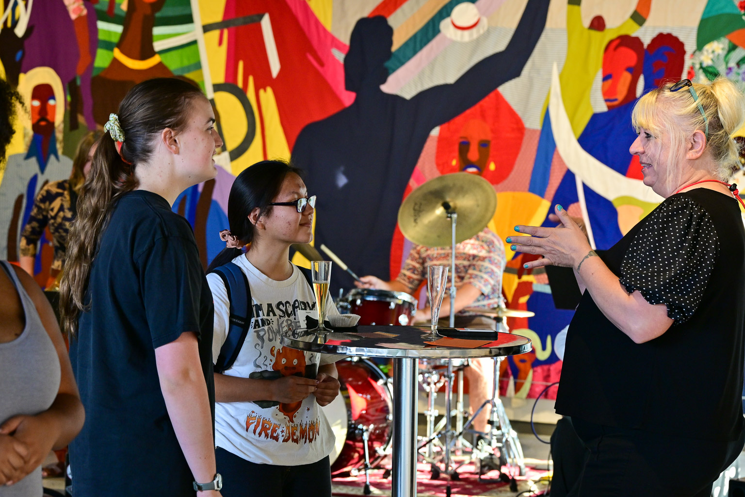 Two students speak with a professor while enjoying refreshments at the “Fall 2025 First-Year Programs Evening at the Museum” event.