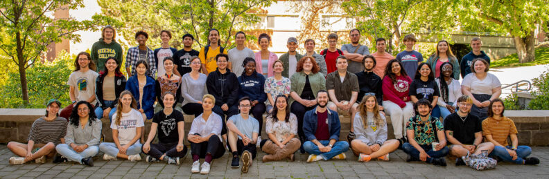 Student participants of the 2022 Summer Undergraduate Research Program sit together outside the CUE building.