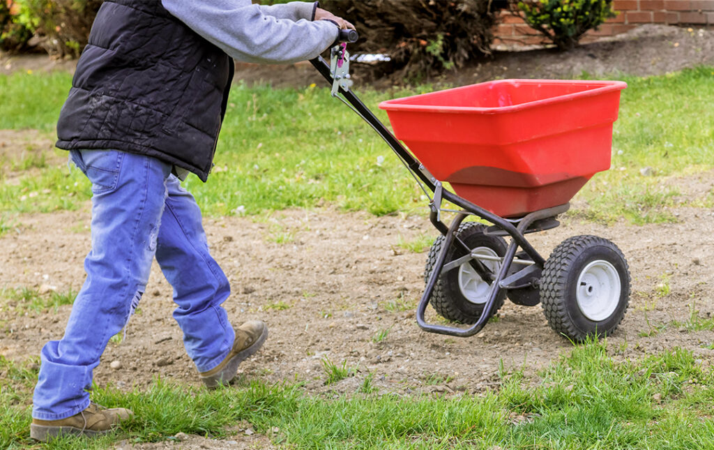 Man pushing a broadcast spreader