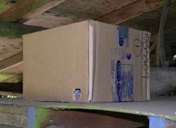 Caja de cartón con un agujero en un costado inferior a la derecha.