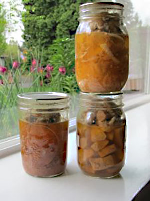 Three jars of home-canned meat showing that raw-packed, lean cuts may not release enough natural juices and fat to fully cover the meat after processing.