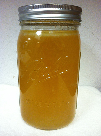 Sealed jar of clear, golden turkey broth after pressure canning.