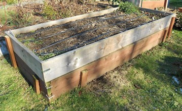 Taller raised beds framed with wood and supported by exterior stakes.