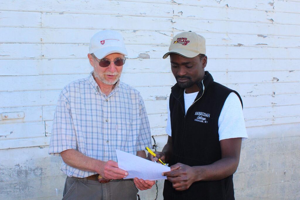 Two people consult a piece of paper. One person looks toward the camera.