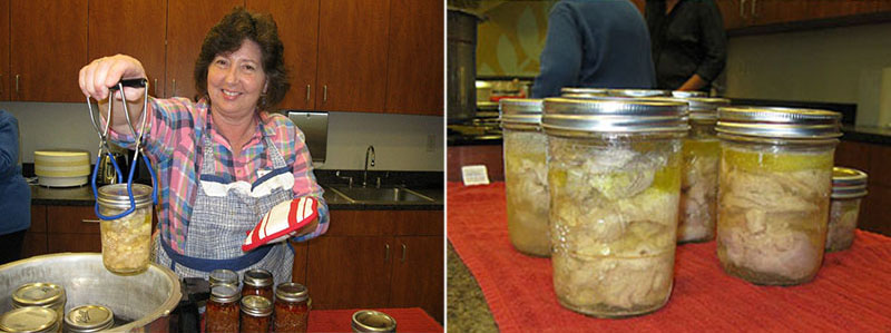 Person lifting a jar of processed raw-packed chicken from a pressure canner, with additional sealed jars of cooked chicken cooling on a towel-covered counter, showing meat covered by natural juices and fat.
