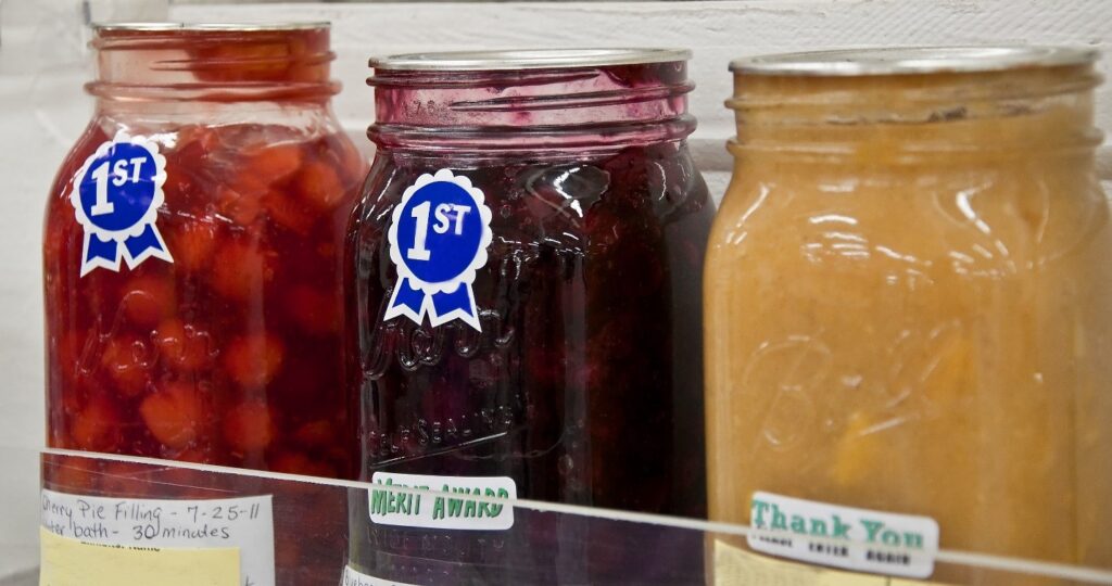 Three jars of home-canned fruits. Two show first place awards.