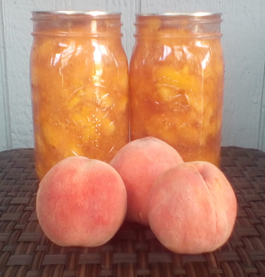 Two jars of peach pie filling with a peach in front of each.