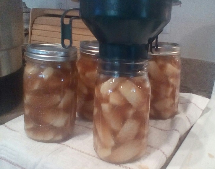 Apple pie filling being added to jars.