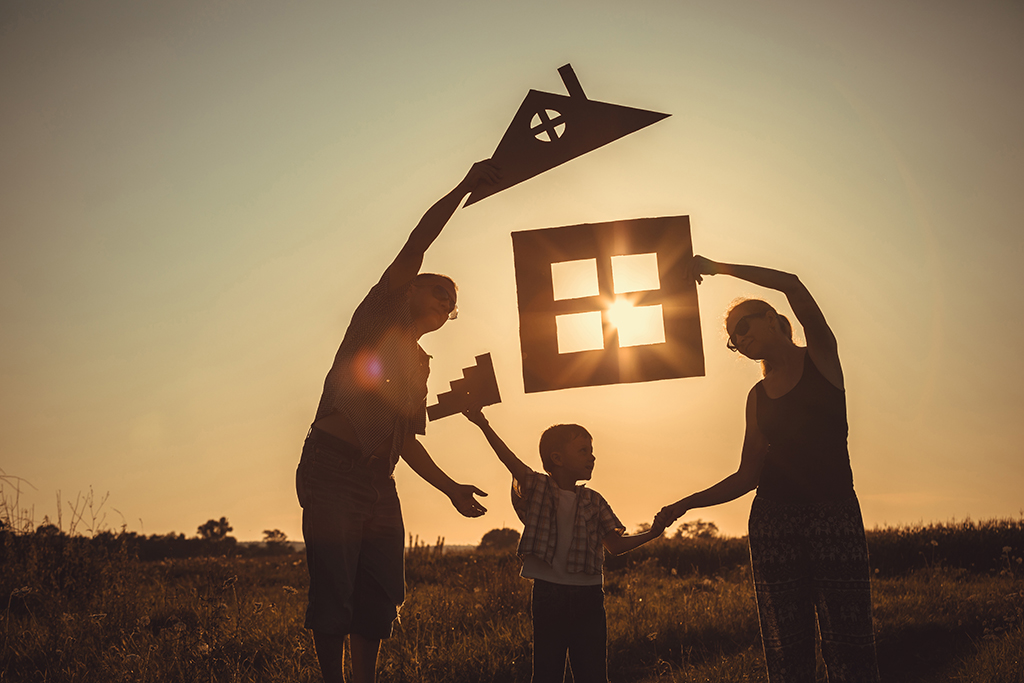 Happy family standing on the field at the sunset time.