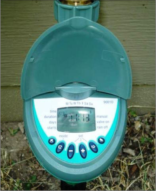 A green hose timer showing the days of the week, time, days, starts, manual, valve on, mode, and rain off labels next to a digital display. 
