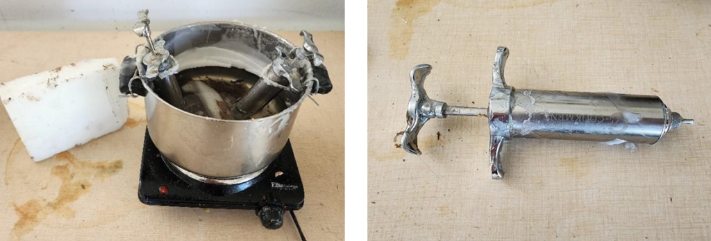 On the left, a hot plate with a pot of wax on the burner and a block of cold wax. On the right, a meat injector with a clipped needle tip. 