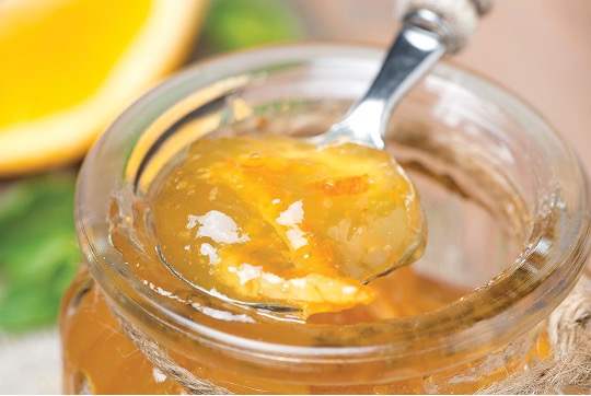 A spoon in a jar of orange marmalade