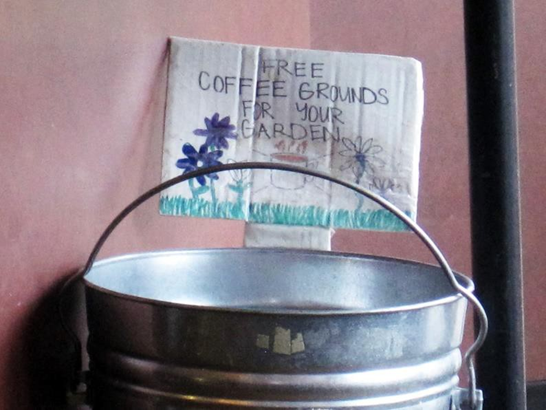 Many coffee shops provide used grounds for their customers. A bucket with a sign reading Free Coffee Grounds for Your Garden.